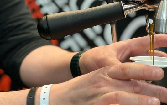Person making an espresso shot using a manual coffee grinder.