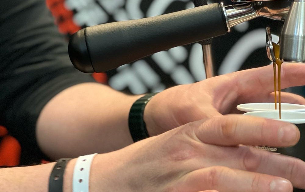 Person making an espresso shot using a manual coffee grinder.